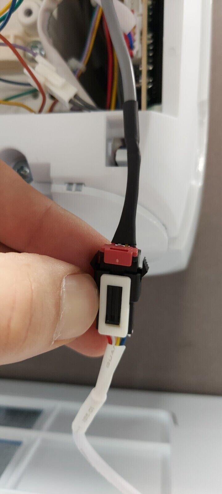 Close-up of a hand holding a cable connector for a WiFi module, part of a Hisense air conditioner installation.