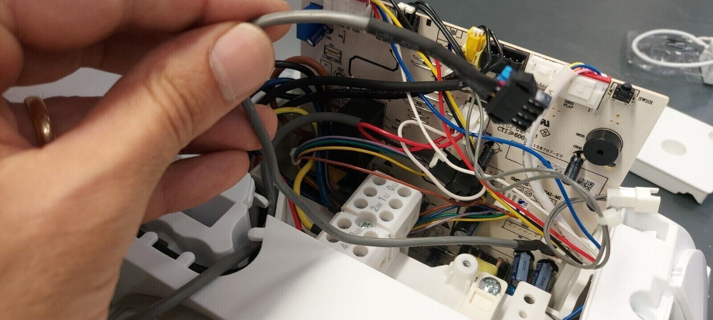 Hand holding a wire inside the control unit of a Modulo WiFi Wireless device for a Hisense air conditioner.