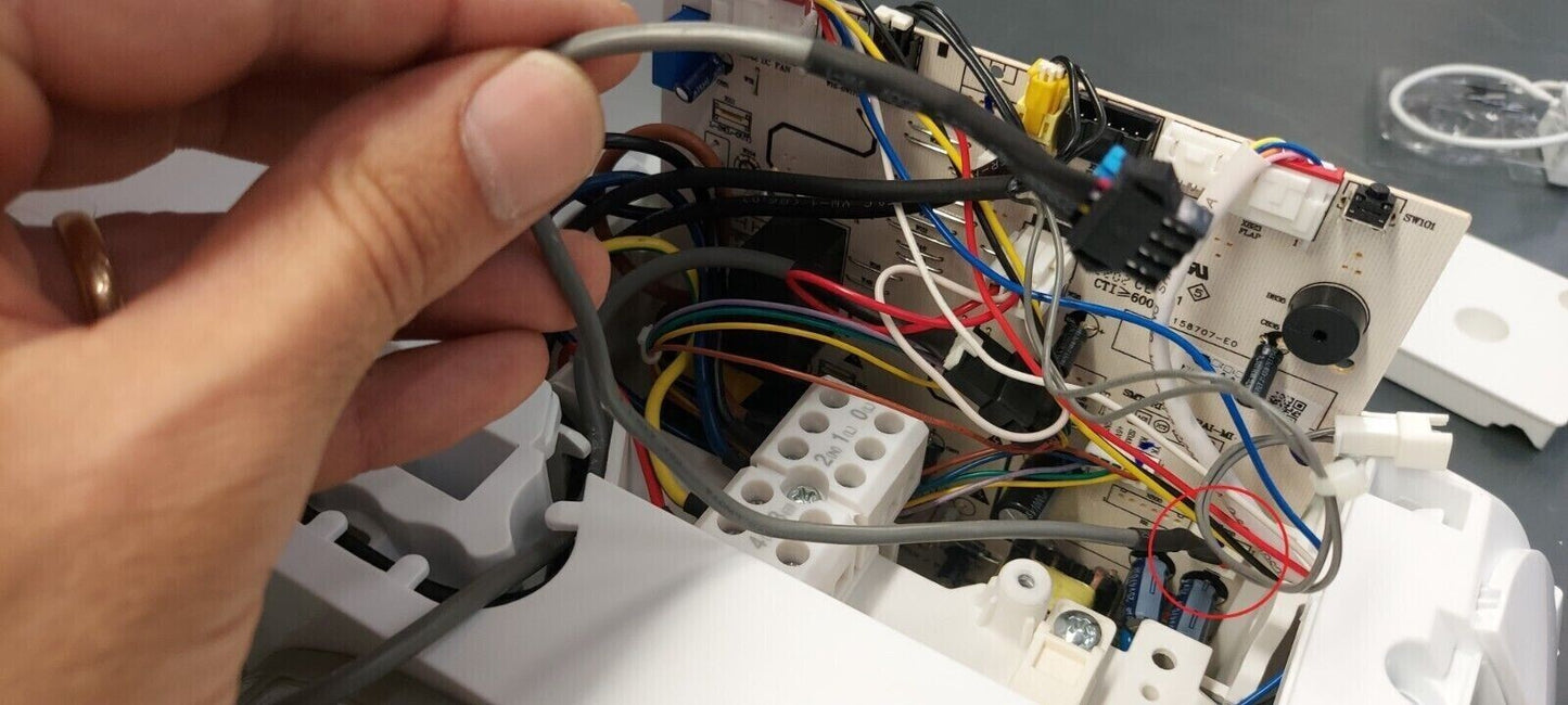 Close-up of wiring inside Modulo WiFi wireless device for Hisense air conditioner with hand holding a cable.
